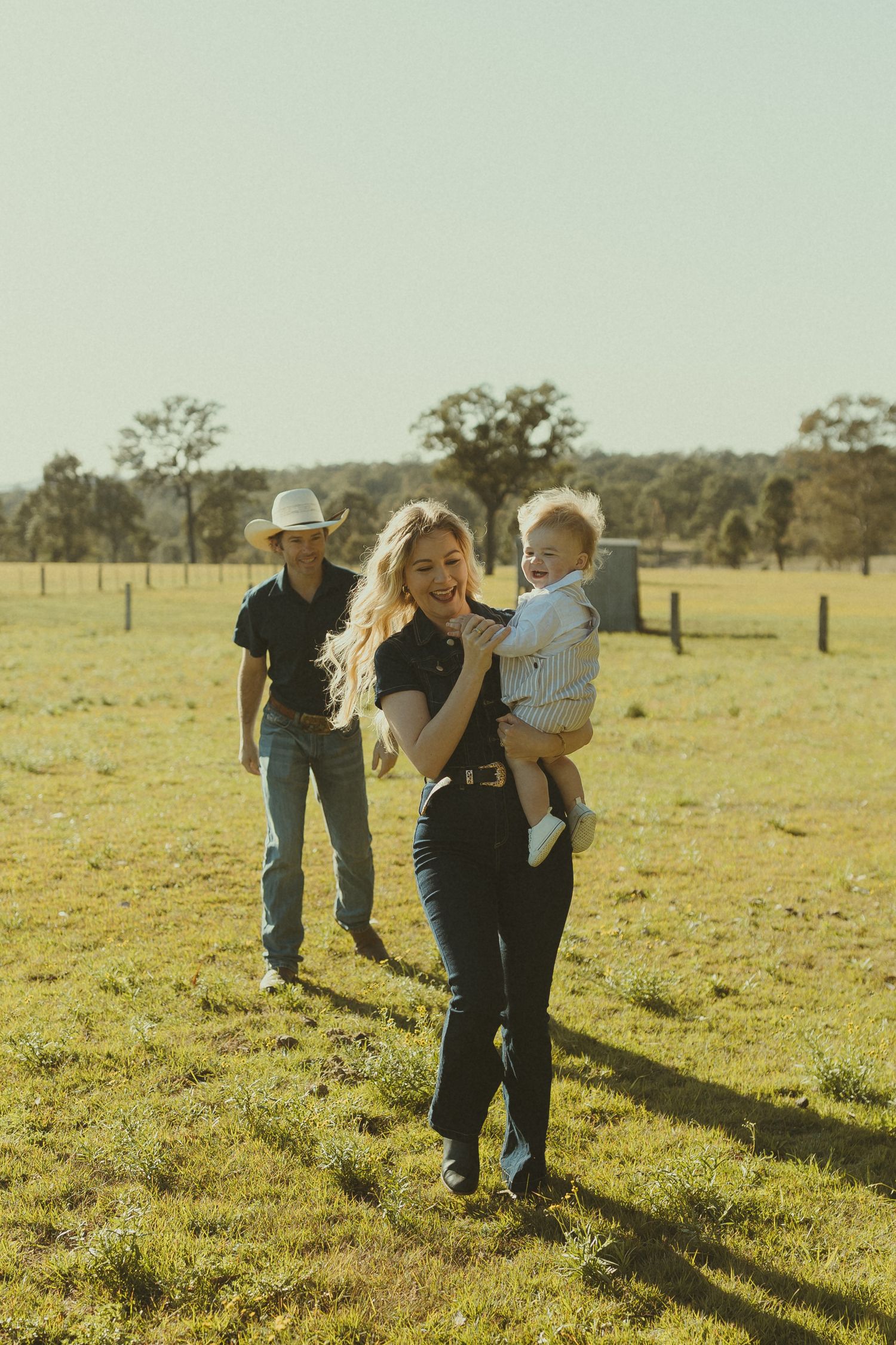 Family enjoying a fun afternoon together in a rural field with golden sunlight casting long shadows.