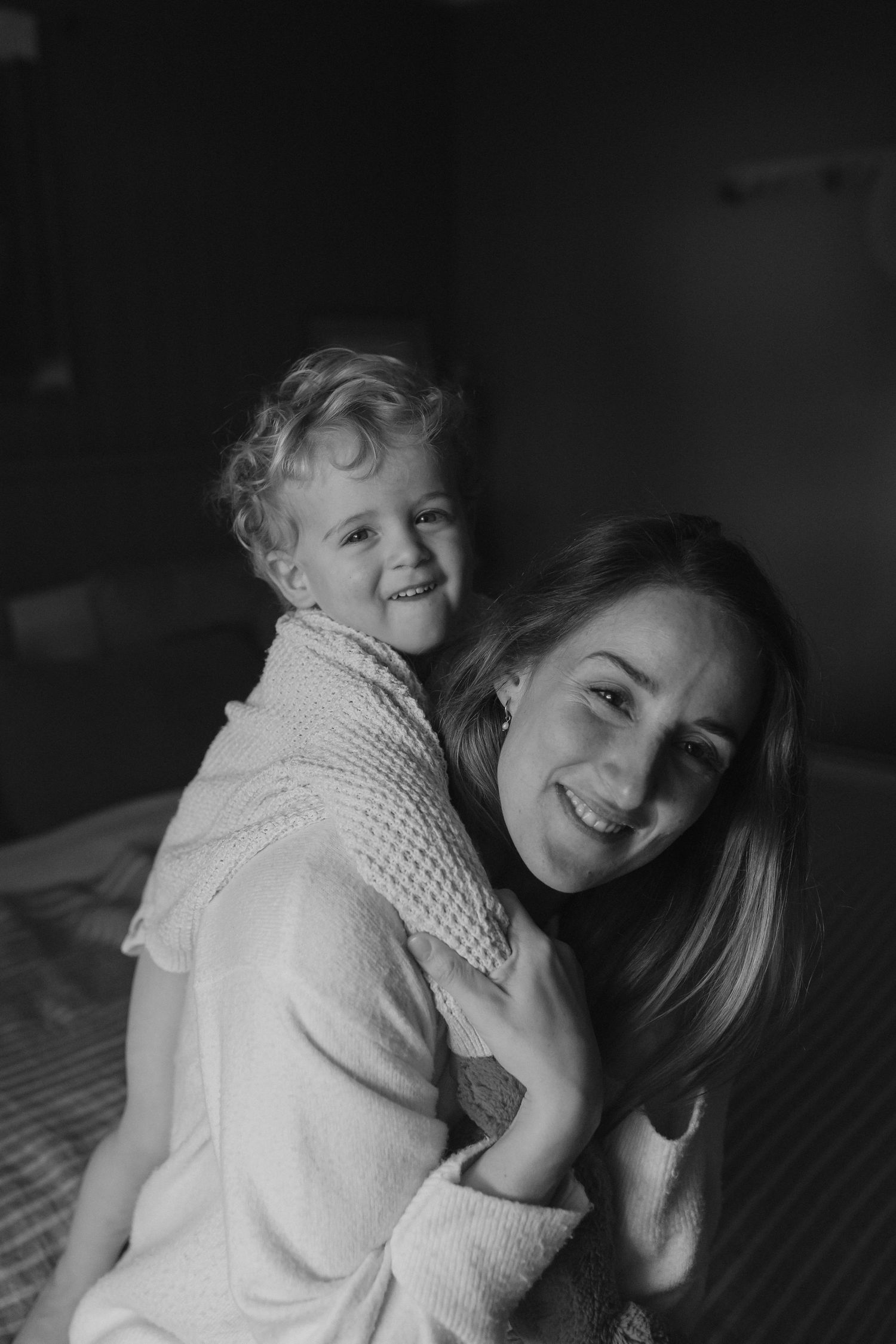Black and white photograph capturing a joyful embrace in an intimate indoor setting.