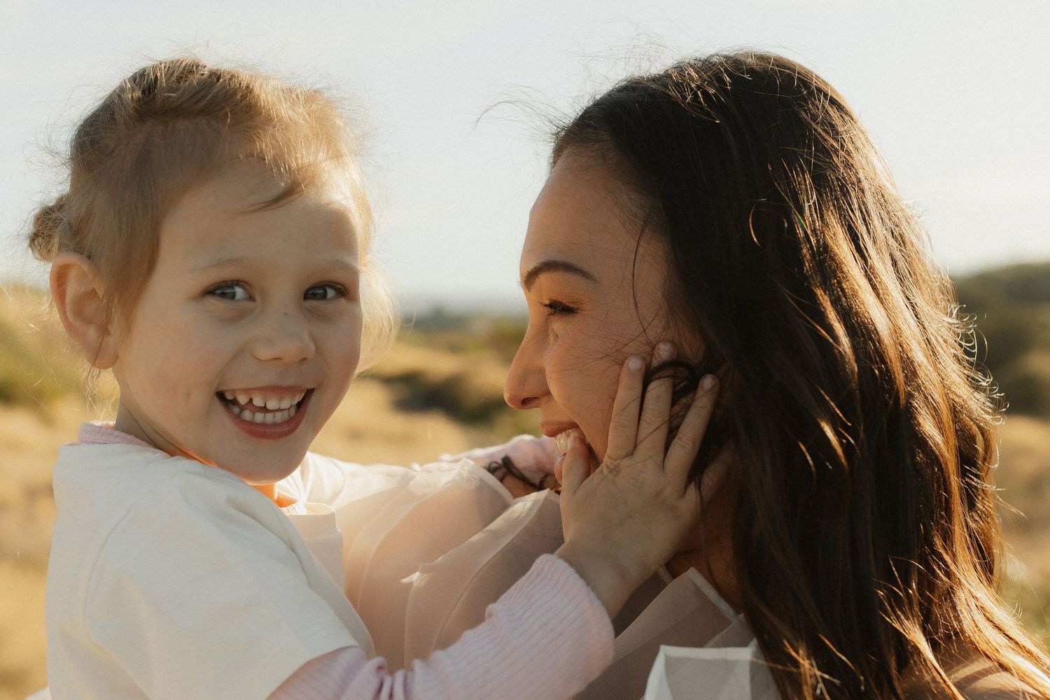 Joyful outdoor moment between parent and child in warm sunlight.