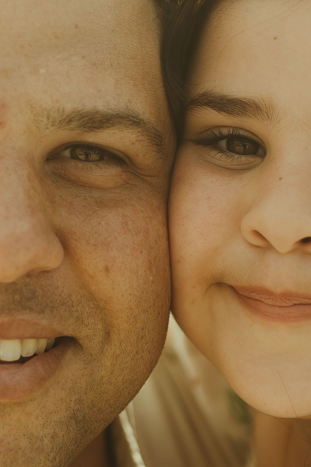 Close-up cropped portrait showing warm smiles and expressions in a romantic golden light.
