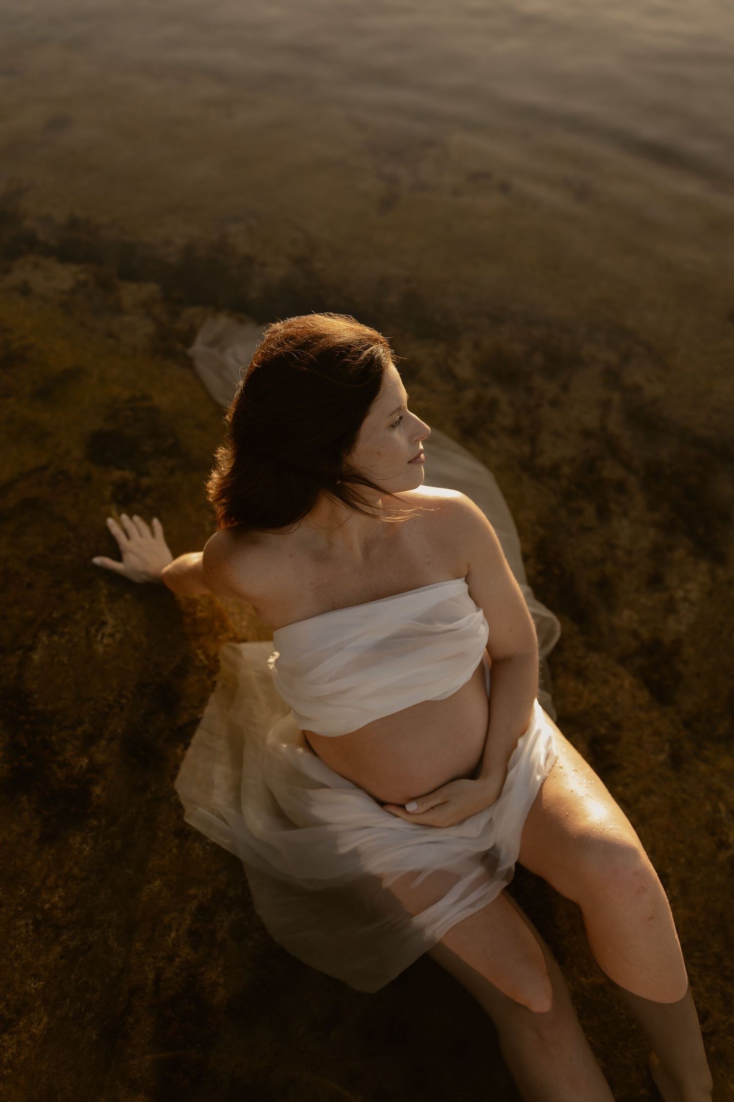 Artistic sequence of a figure in white fabric moving gracefully against a dark background in dramatic lighting.
