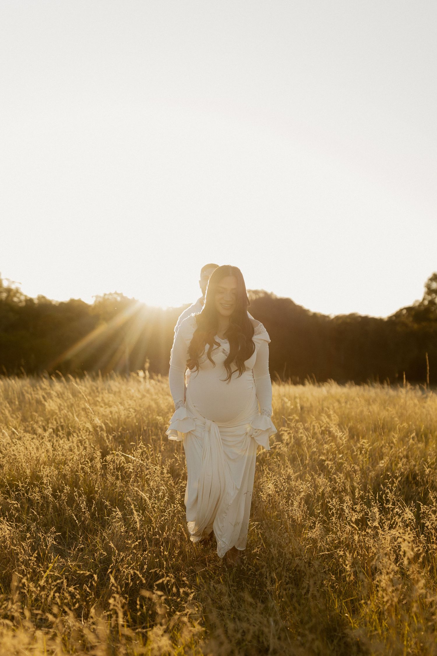A dreamy golden hour photoshoot in a wildflower meadow with a figure in a flowing white dress.