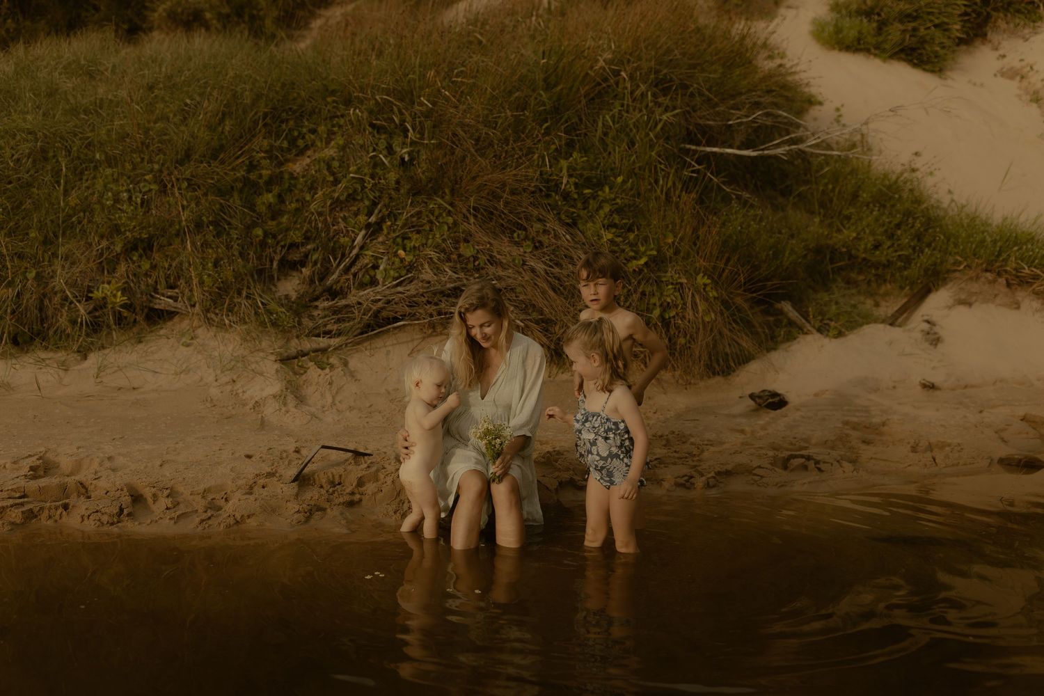 Family enjoying time together at the water's edge during golden hour.