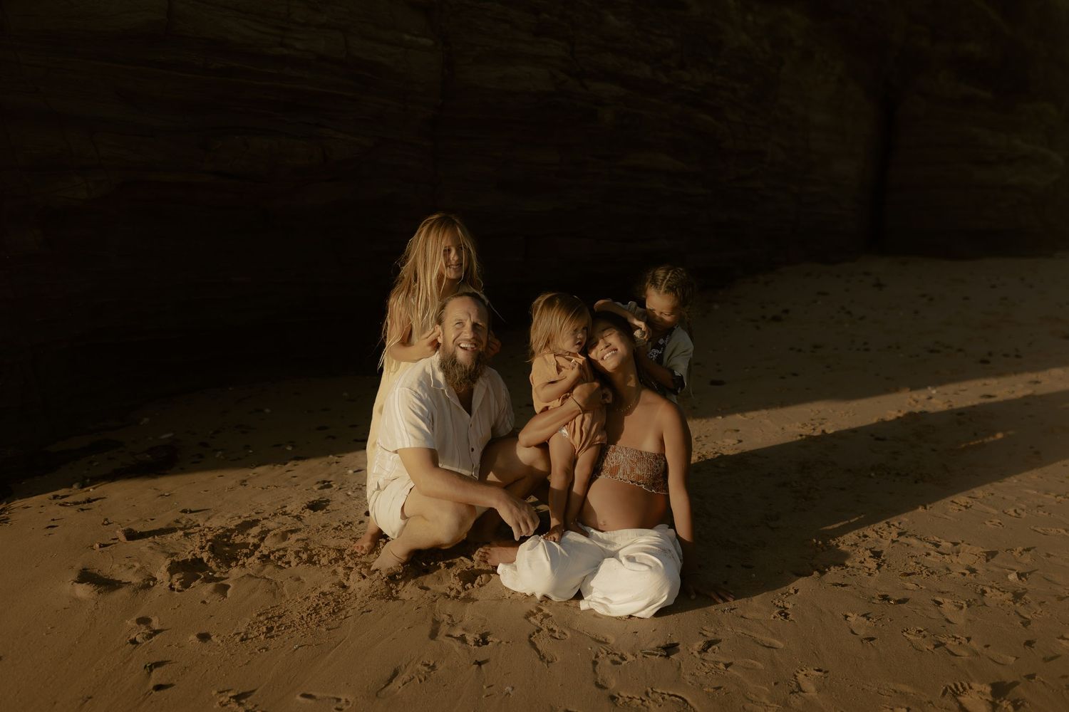 Group gathered on beach at dusk creating candid moments in natural lighting.