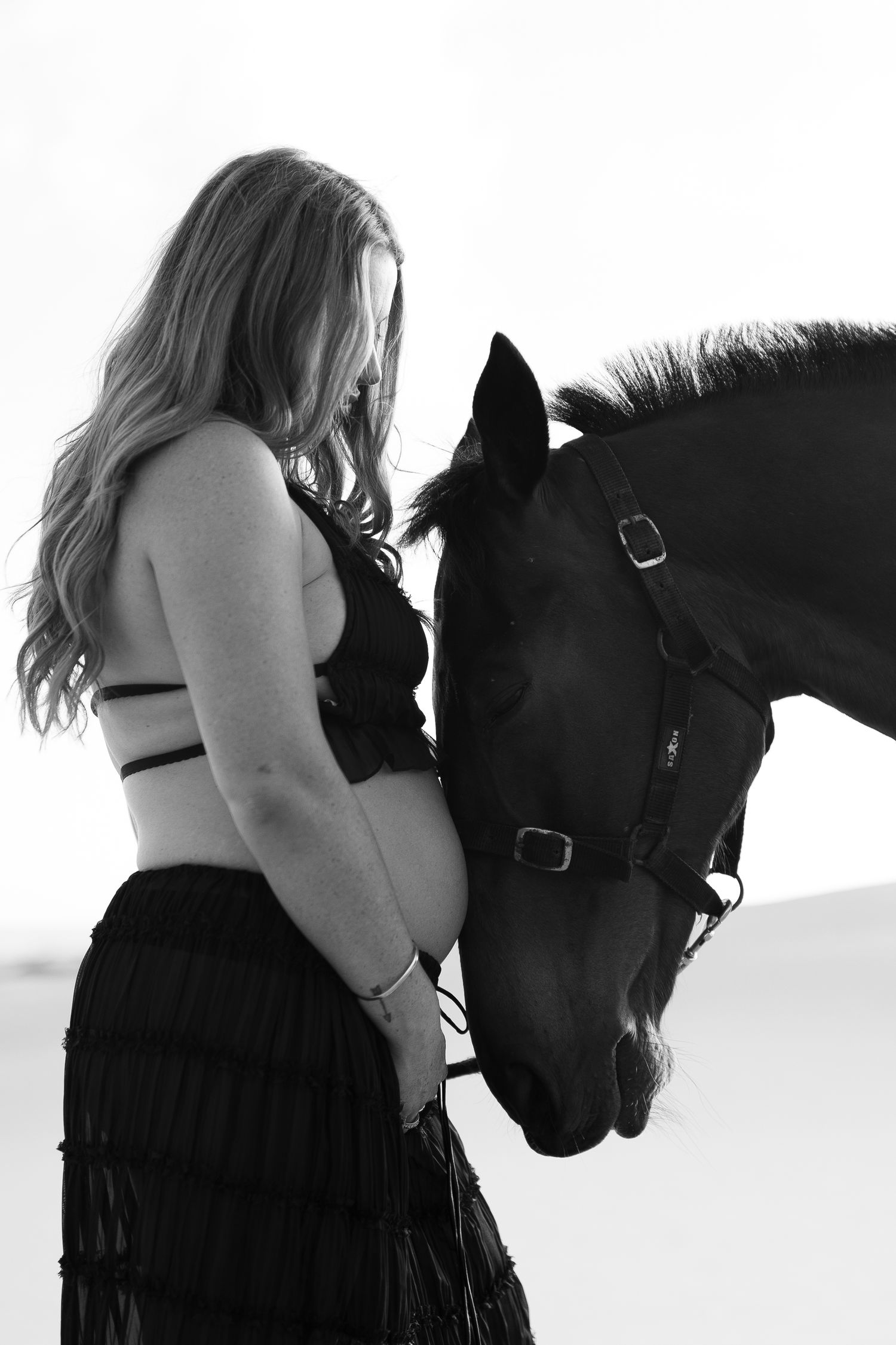 Intimate black and white portraits show a tender moment between a person and a black horse.
