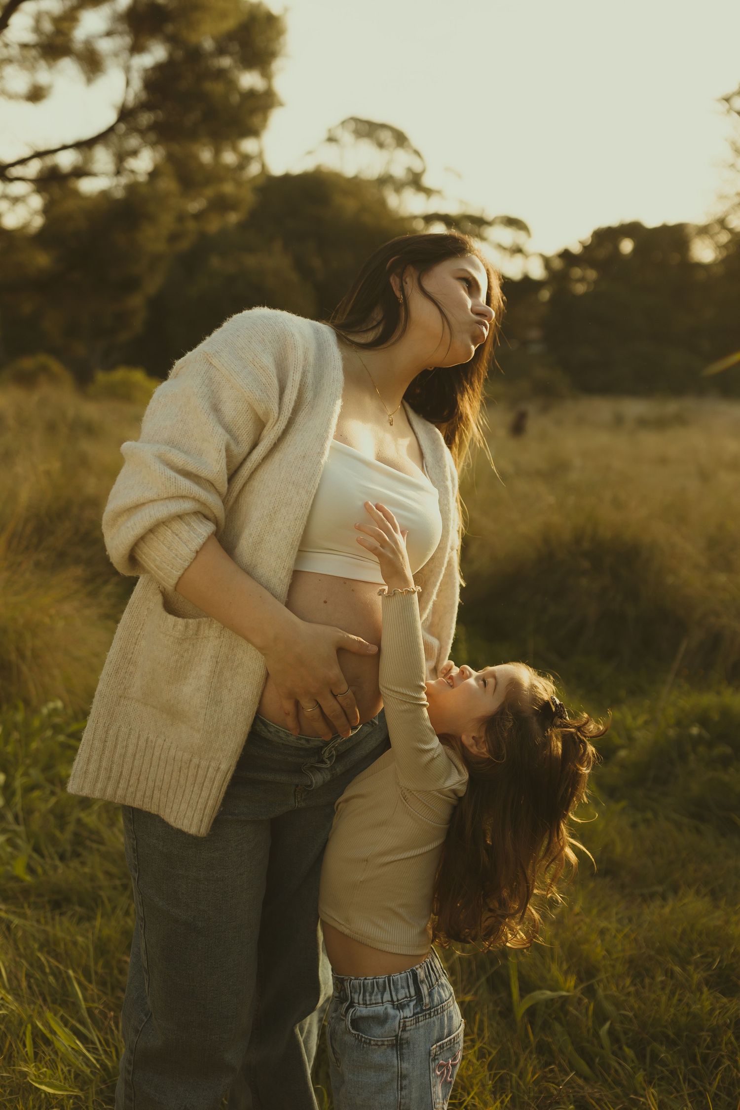An intimate embrace between a couple in casual clothing against a warm sunset backdrop.