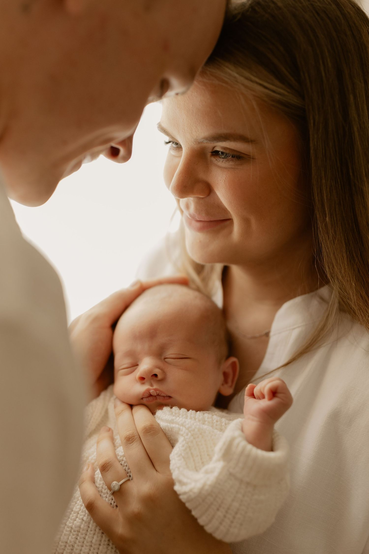 Sweet moment captured in warm lighting as someone gently holds a sleeping newborn.