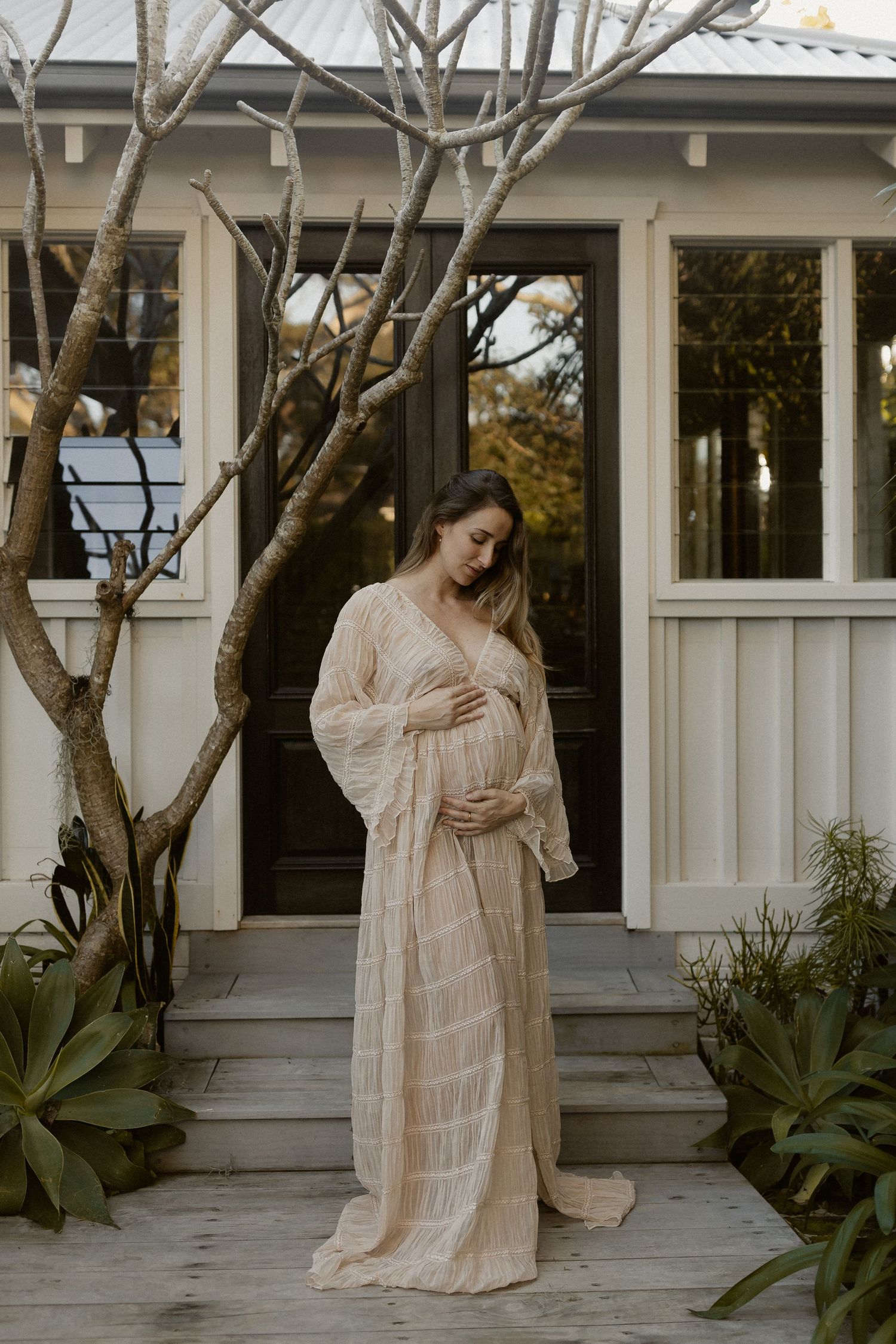 A series of five consecutive photographs showing a person in a flowing cream-colored dress posing against a white building.