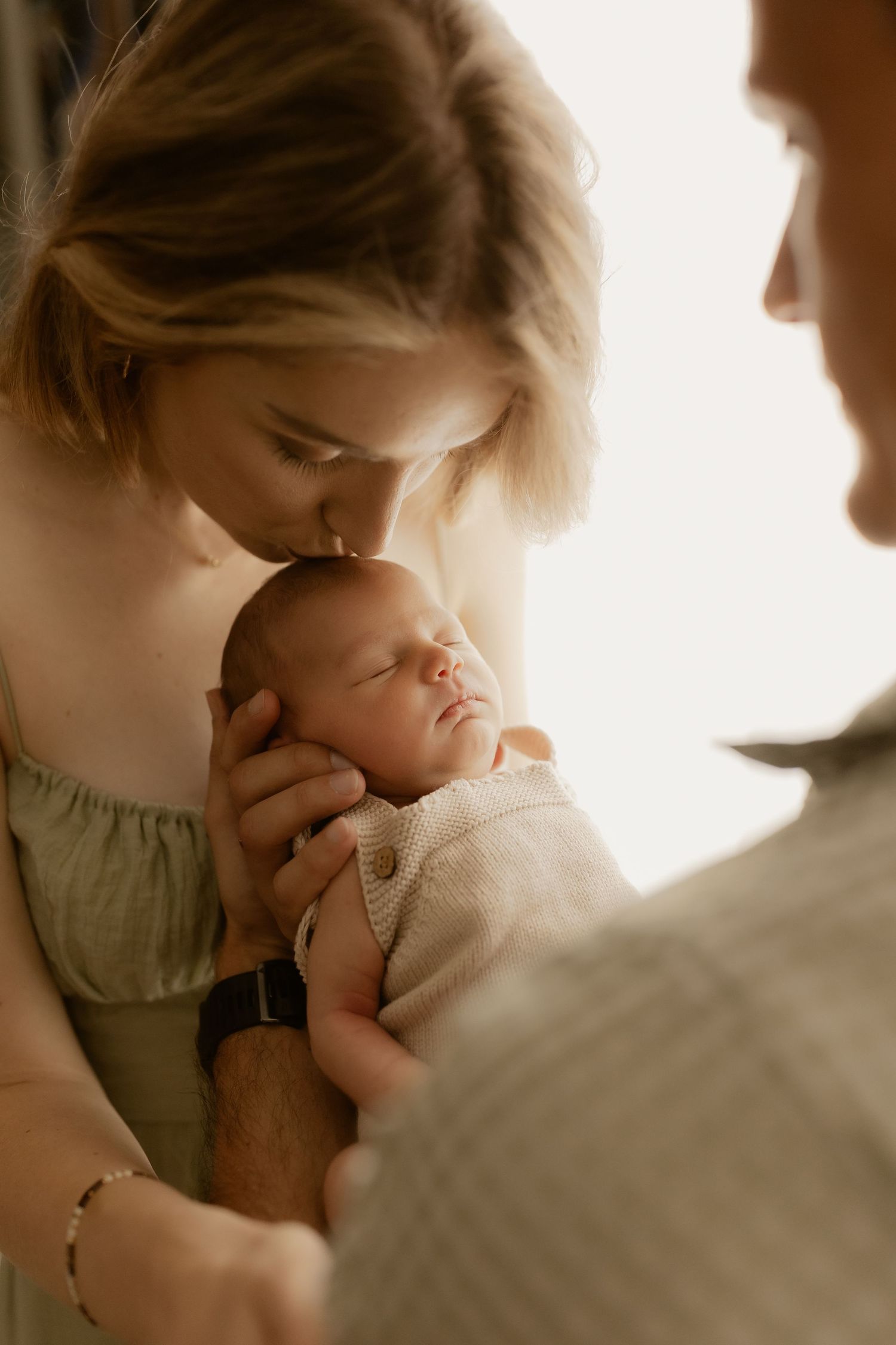 Close-up series of parents sharing gentle kisses with their newborn baby.