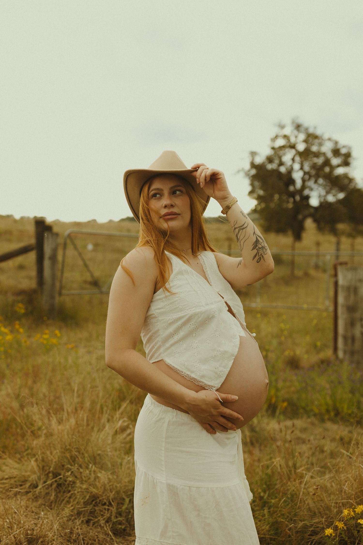 A white sundress is worn in a rustic outdoor setting with golden light and natural scenery.