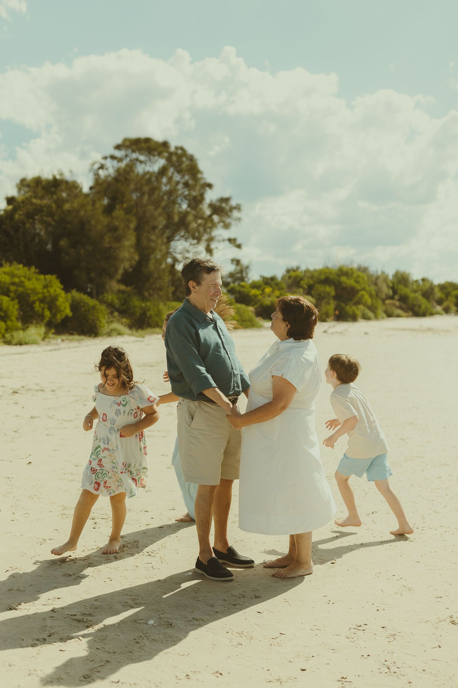 Family enjoying a tender moment together while walking barefoot on a pristine beach.