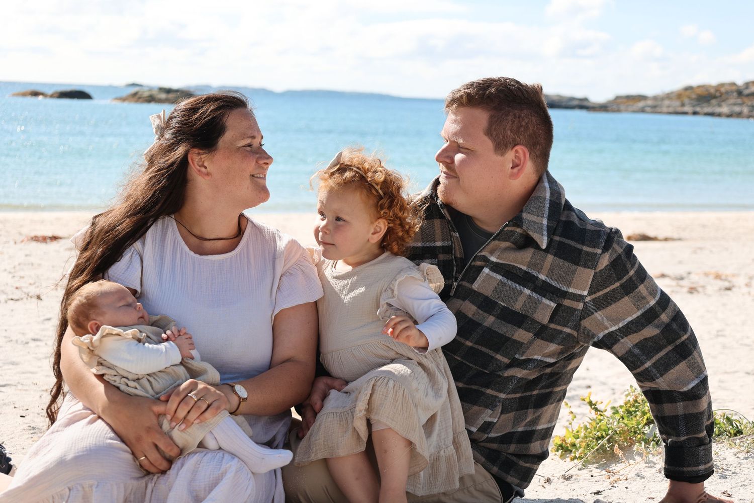 Family enjoying a sunny day together at a scenic beach with crystal blue water.
