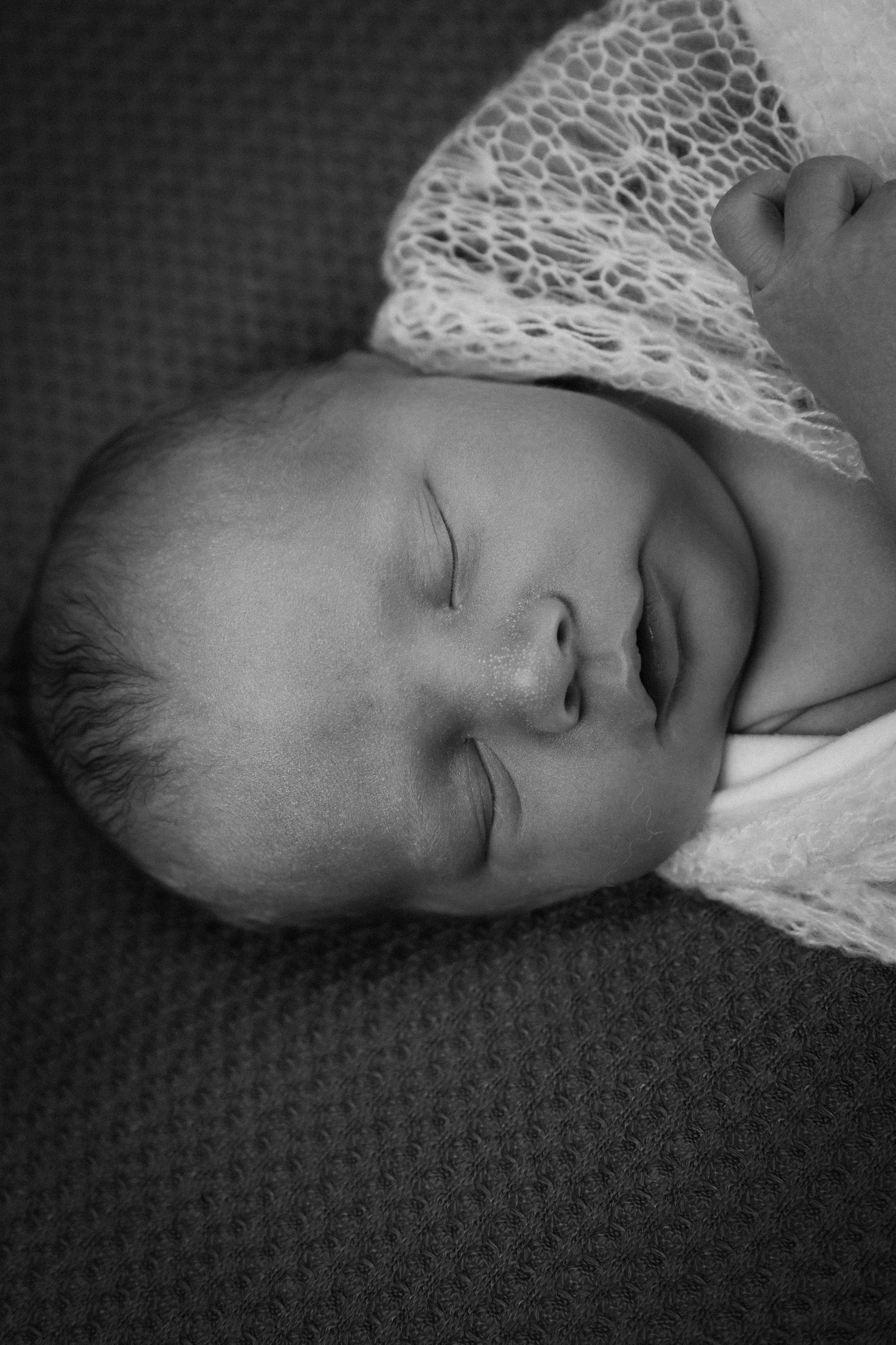 Peaceful sleeping baby in black and white wearing delicate lace clothing.