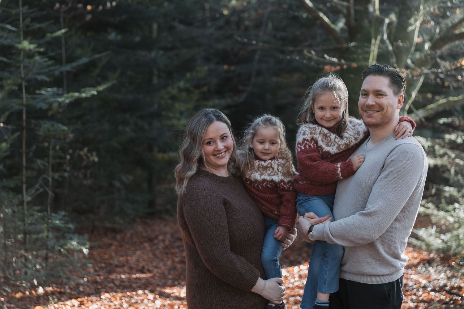 Family walking through an evergreen forest on a winter day with snow on the ground.