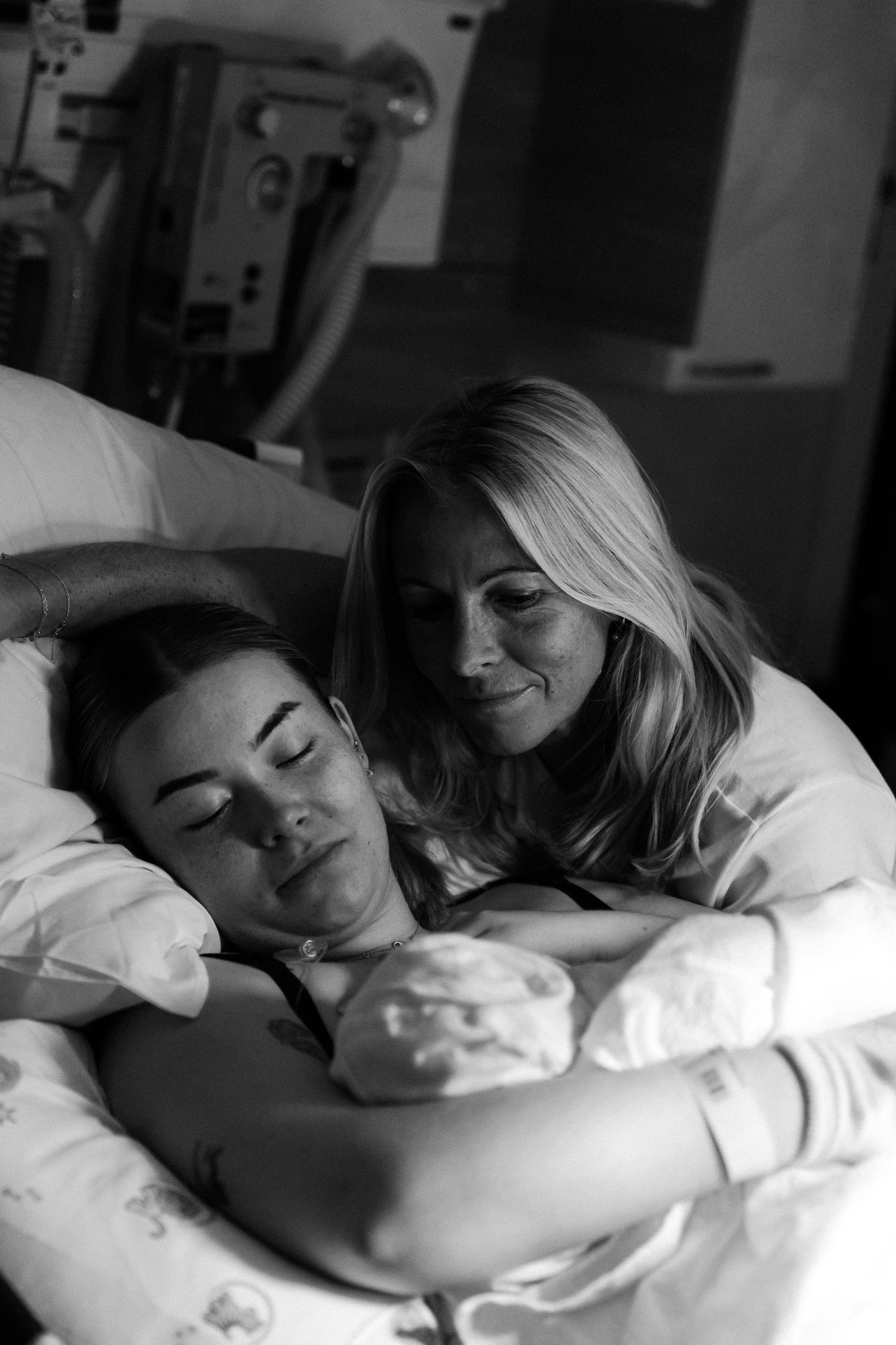 A tender black and white photograph shows two people sharing an intimate moment in a hospital room.
