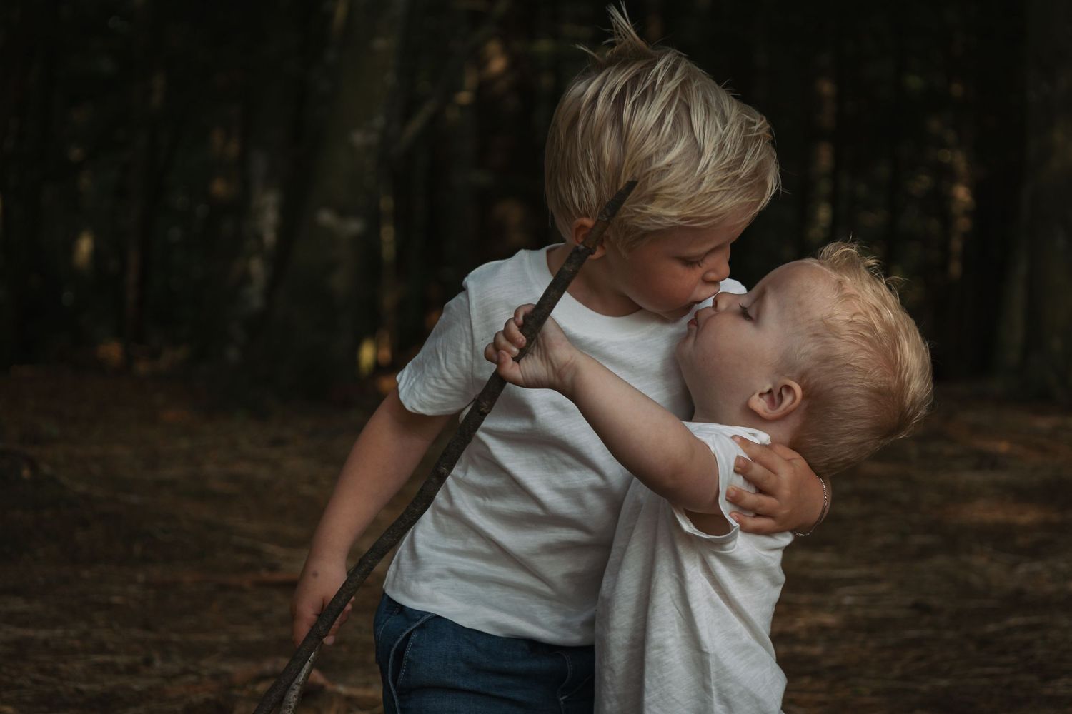 Candid playful moment between two children in a forest setting.