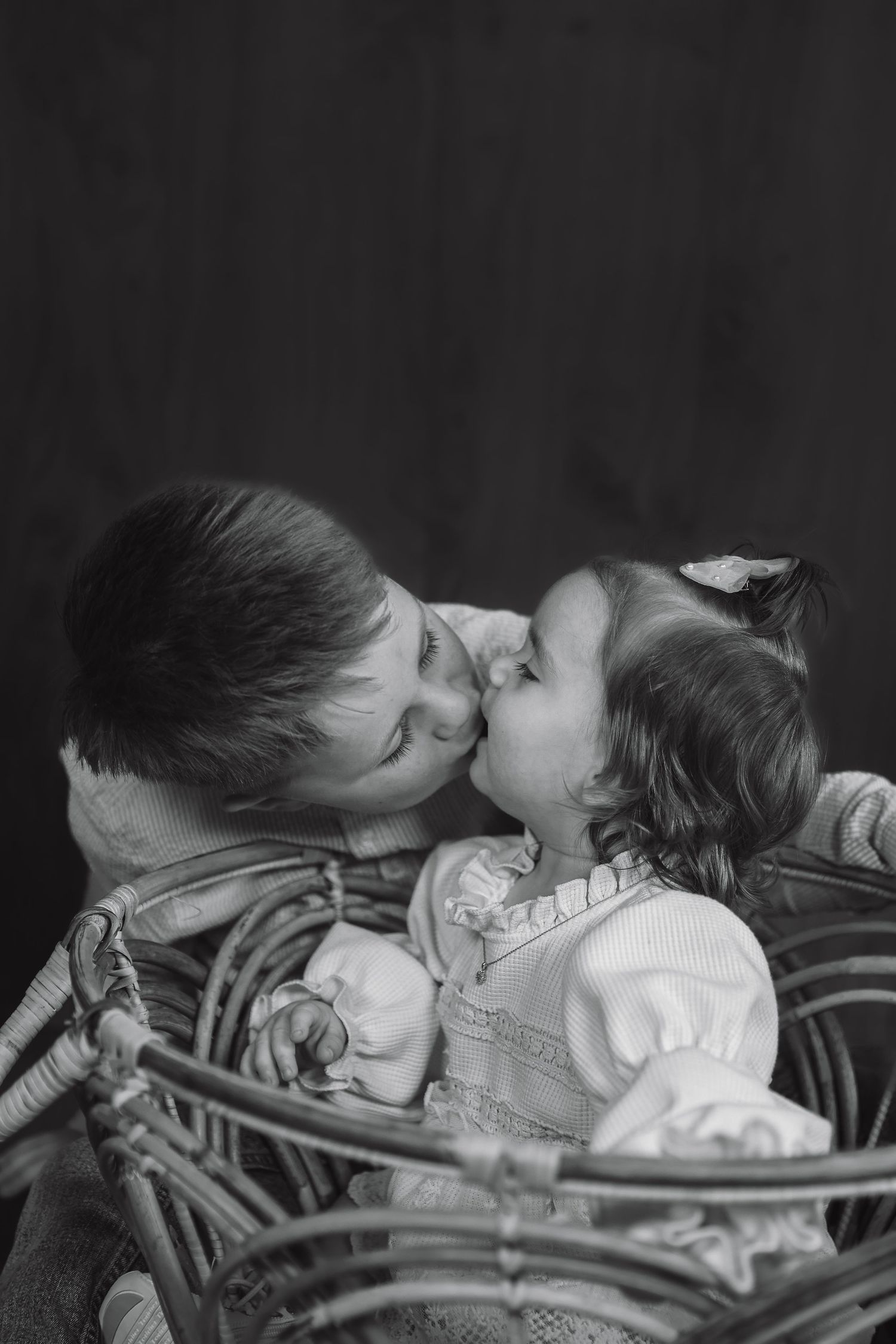 Black and white portrait of two children sharing an affectionate moment.