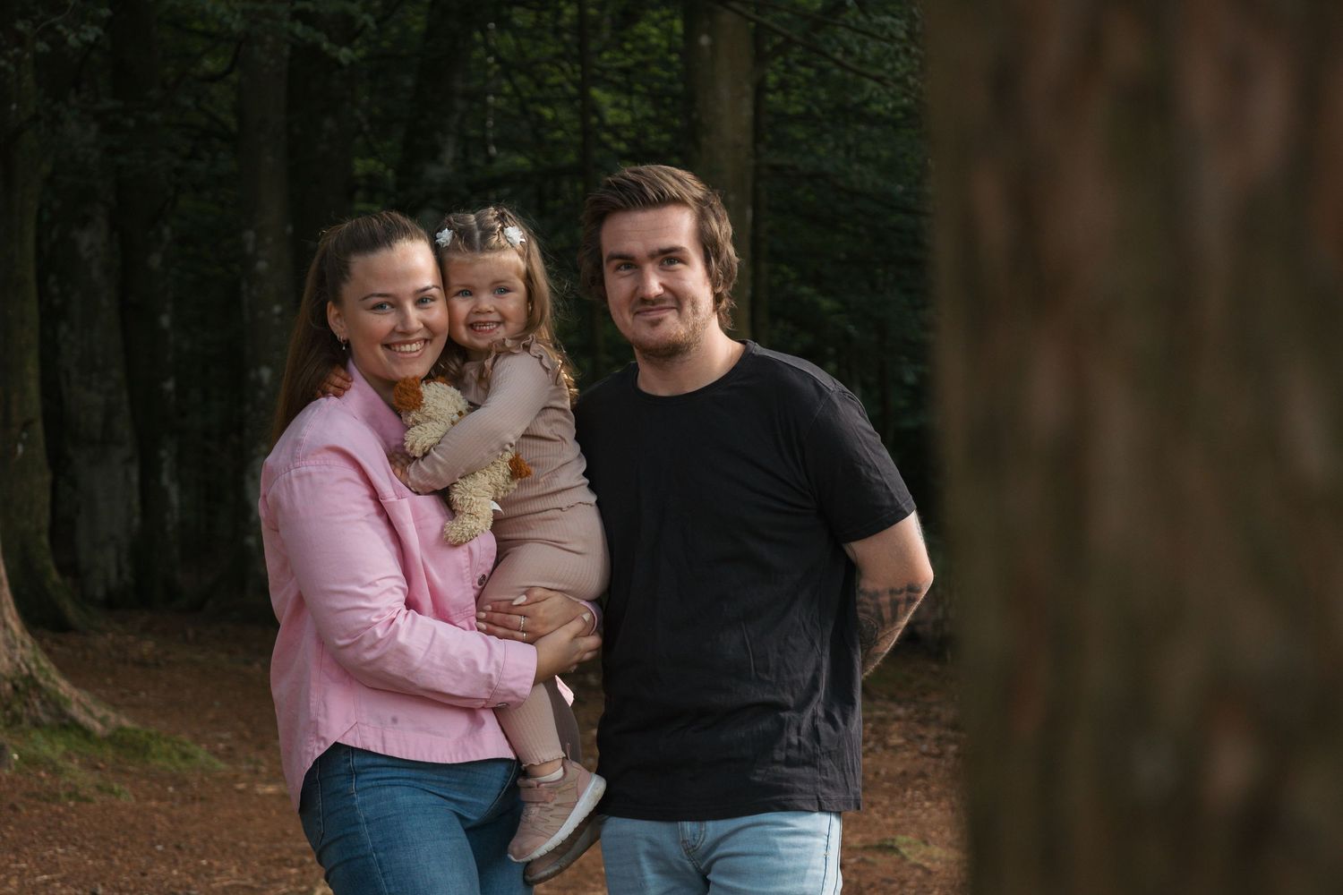 A casual family portrait in a wooded setting during golden hour.