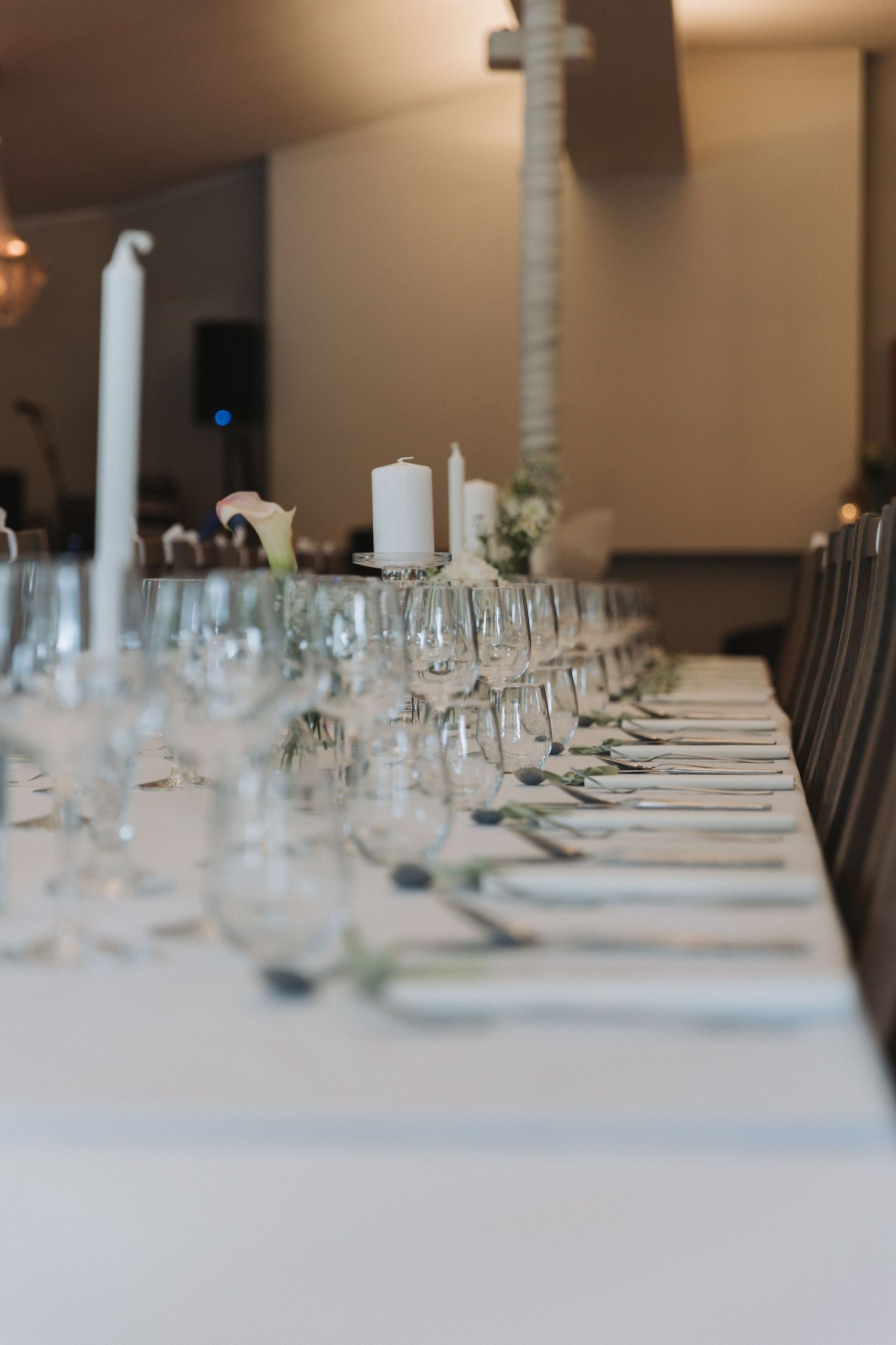Elegant long banquet table set with crystal glasses, white candles, and fine dinnerware for a formal event.