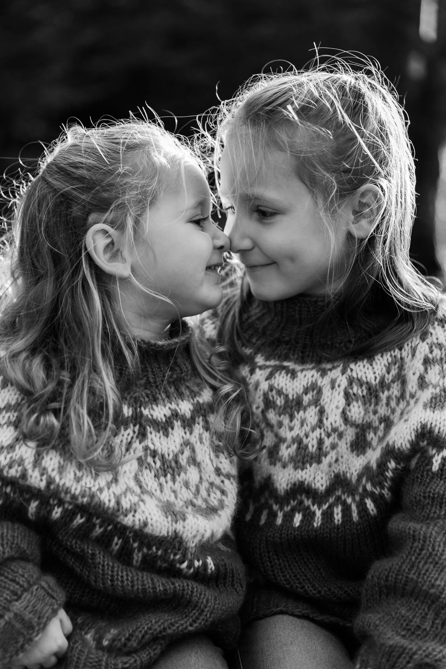 Black and white portrait of two children in matching Nordic sweaters sharing an intimate moment together.