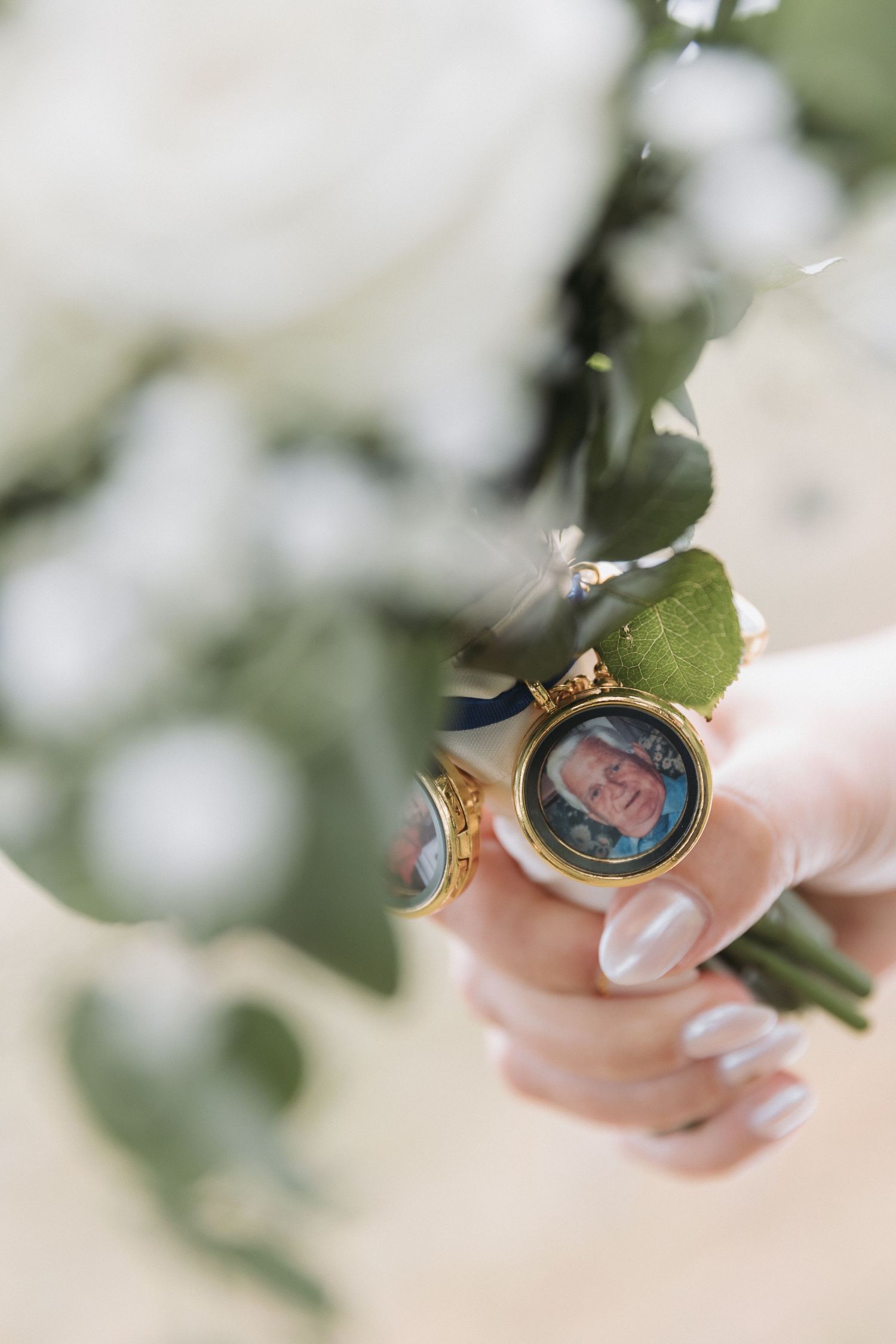 Close-up of bridal bouquet with gold locket charm containing a memorial photo of a loved one.