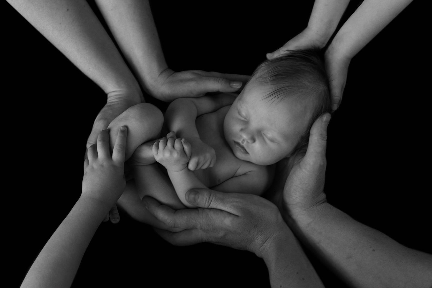 A black and white artistic photo series showing close-up details of hands and feet against a dark background.
