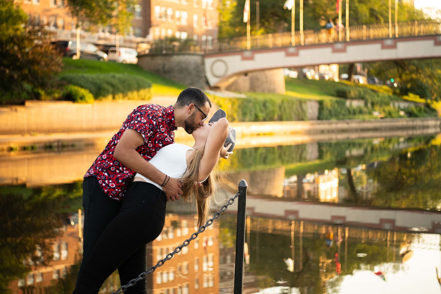 Couple sharing an intimate moment by a reflecting pool at sunset.