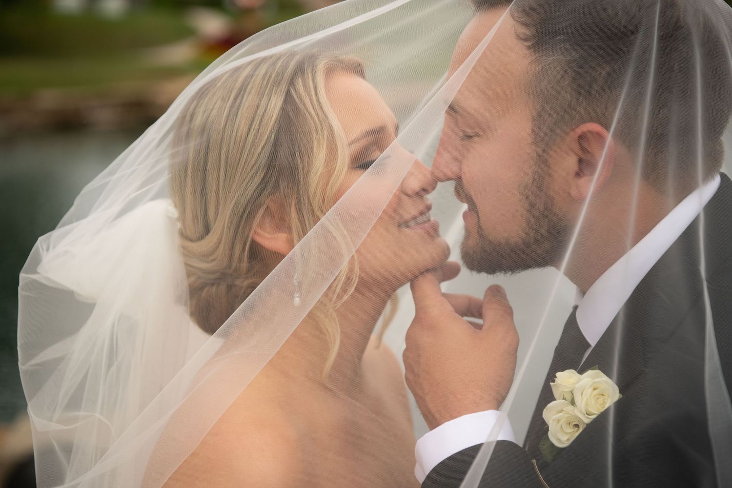 A romantic wedding moment captured through delicate veil covering the couple during an intimate portrait.