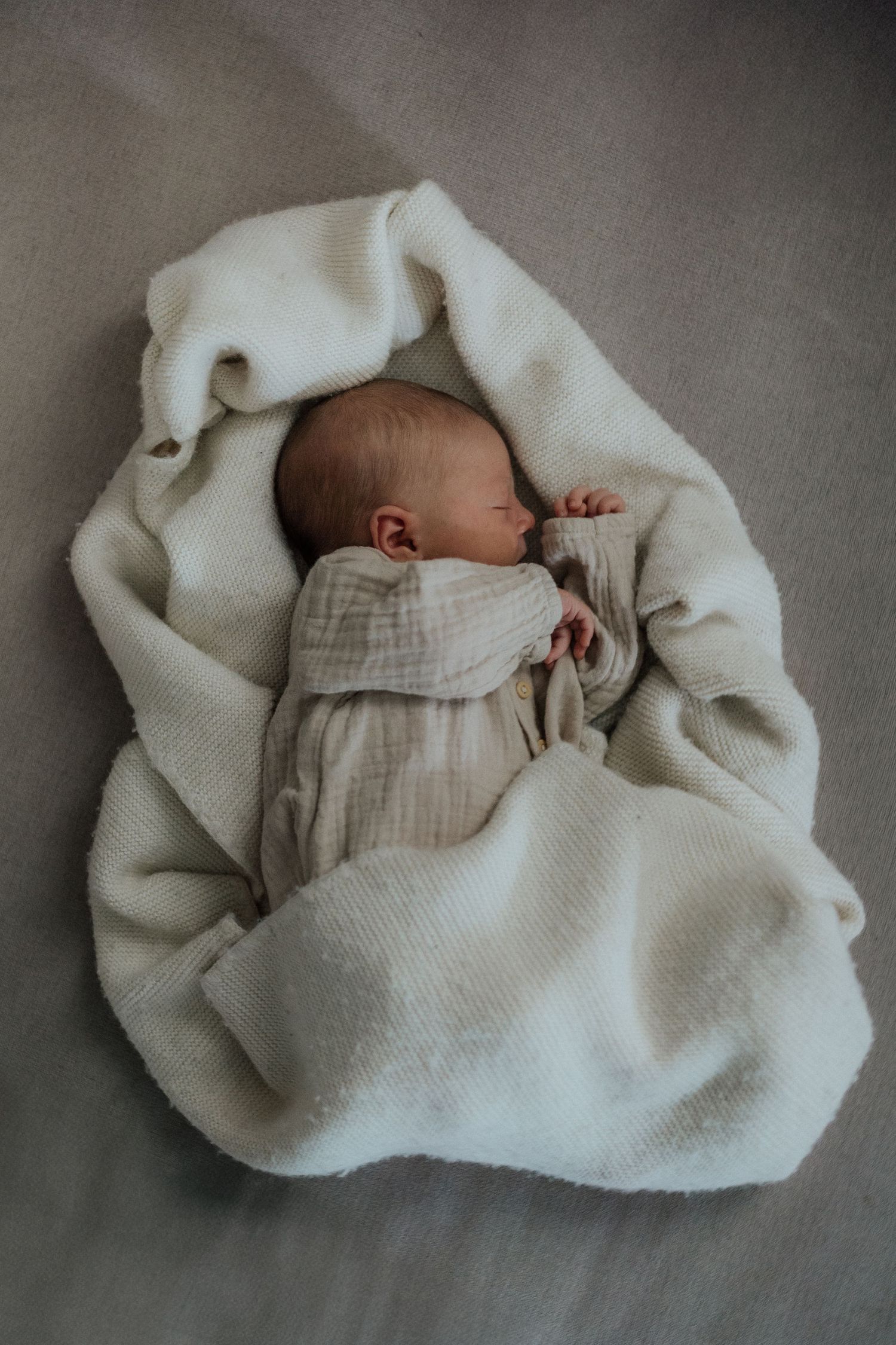 Neugeborenes Baby eingewickelt in Tuch – minimalistisches Babyshooting