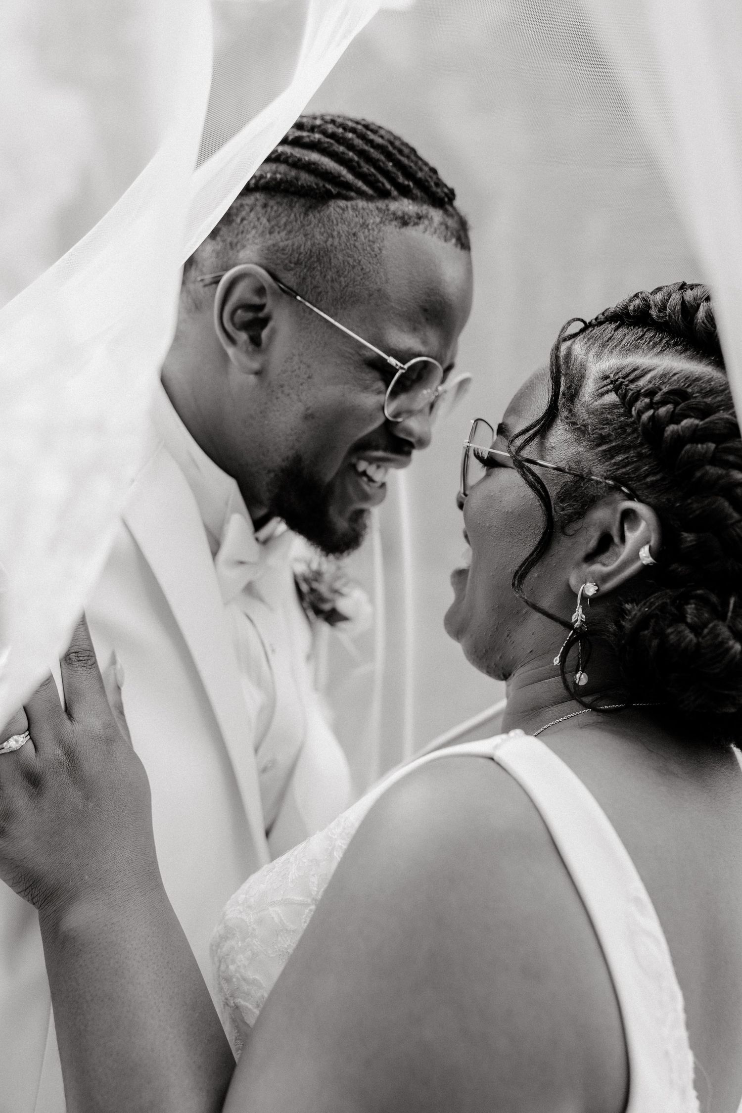 A tender black and white portrait of newlyweds sharing an intimate moment under a veil.