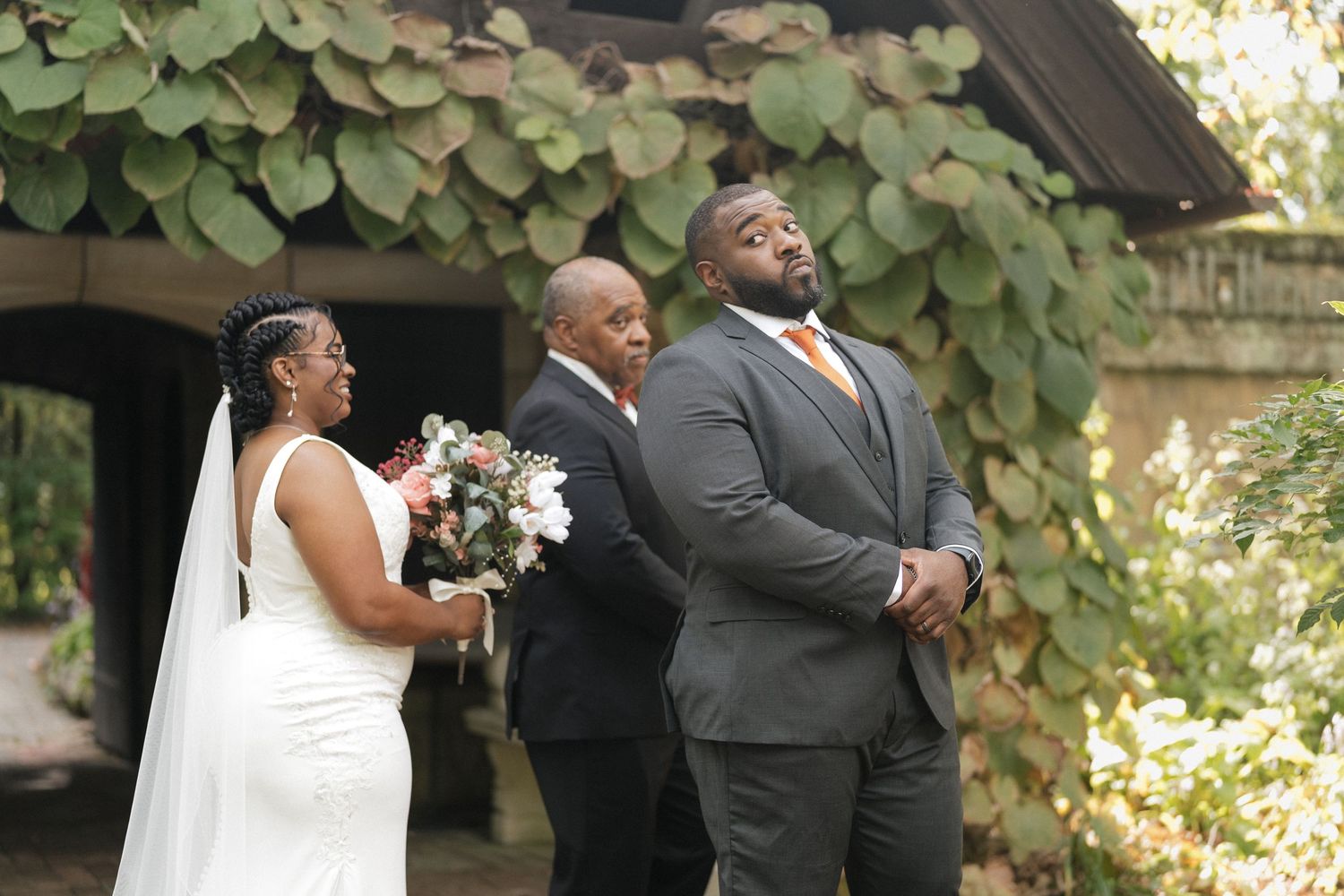 Wedding party members pose together outdoors surrounded by lush greenery.