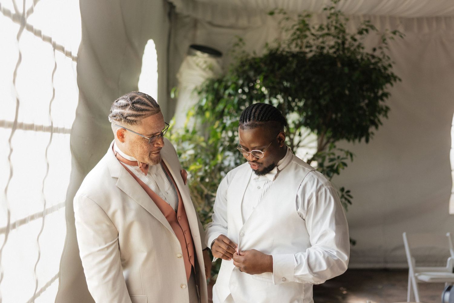 Groomsmen share a lighthearted moment while getting ready in a bright indoor venue.