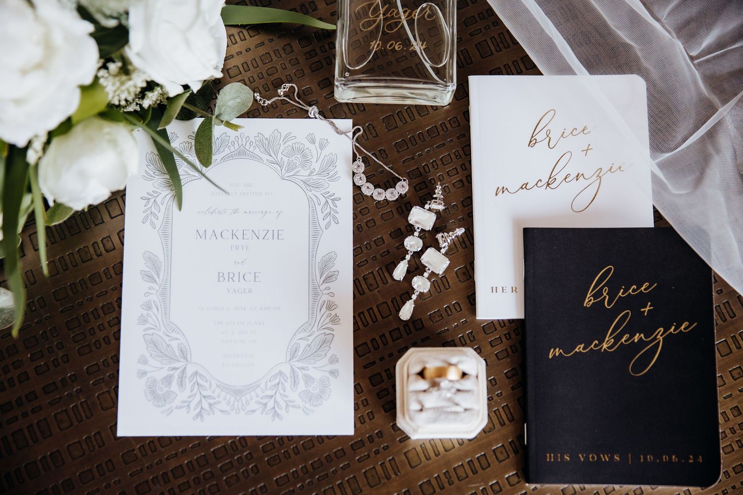 Elegant wedding stationery and invitations arranged with white flowers and decorative elements on dark surface.