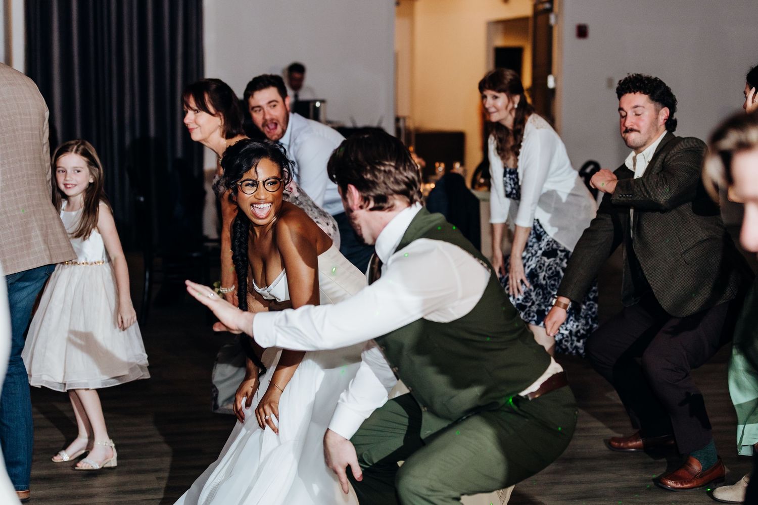 Wedding reception dance party with guests in formal attire dancing energetically on the dance floor.