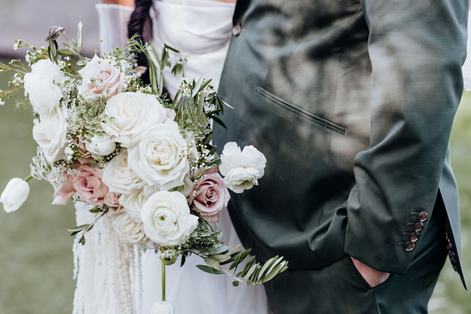 Elegant wedding bouquet details with white and pink roses against formal attire.