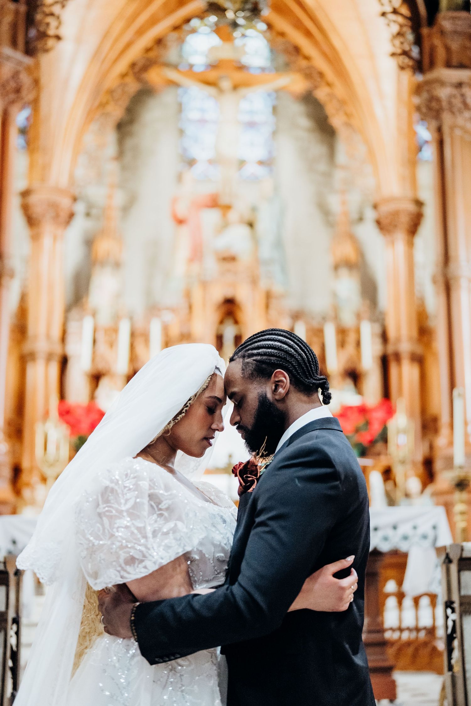 A tender moment captured in a beautiful cathedral with golden arches and stained glass windows.