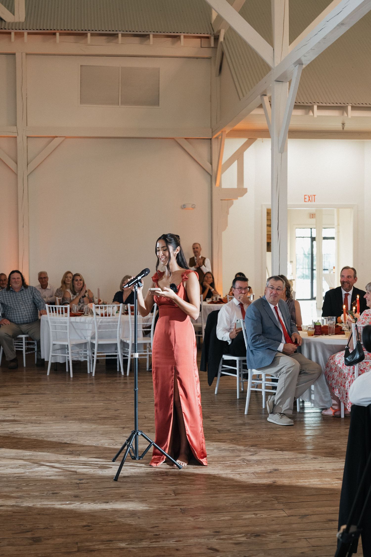 Wedding party dancing and celebrating in a rustic venue with wooden floors and white walls.