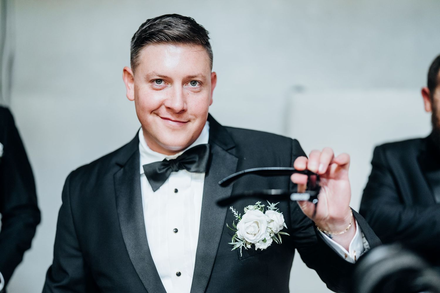 Group of men in formal black tuxedos and bow ties at a wedding event.