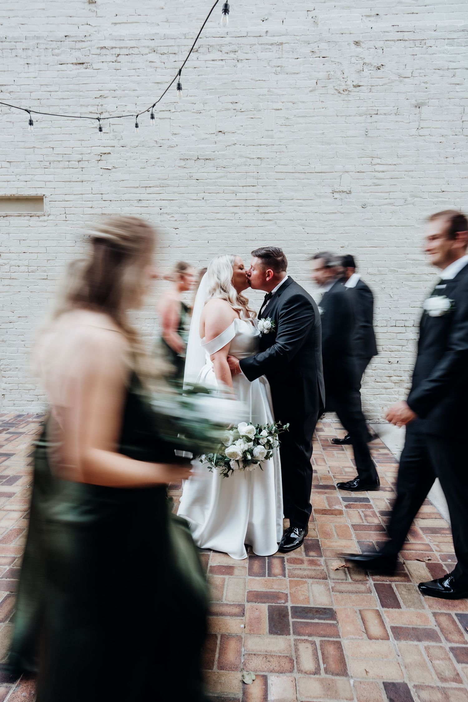 Motion-blur wedding photo with string lights and exposed brick walls creating a dynamic atmosphere.