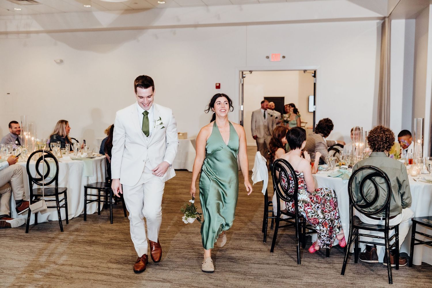 Wedding reception venue with black chiavari chairs and minimalist white decor.