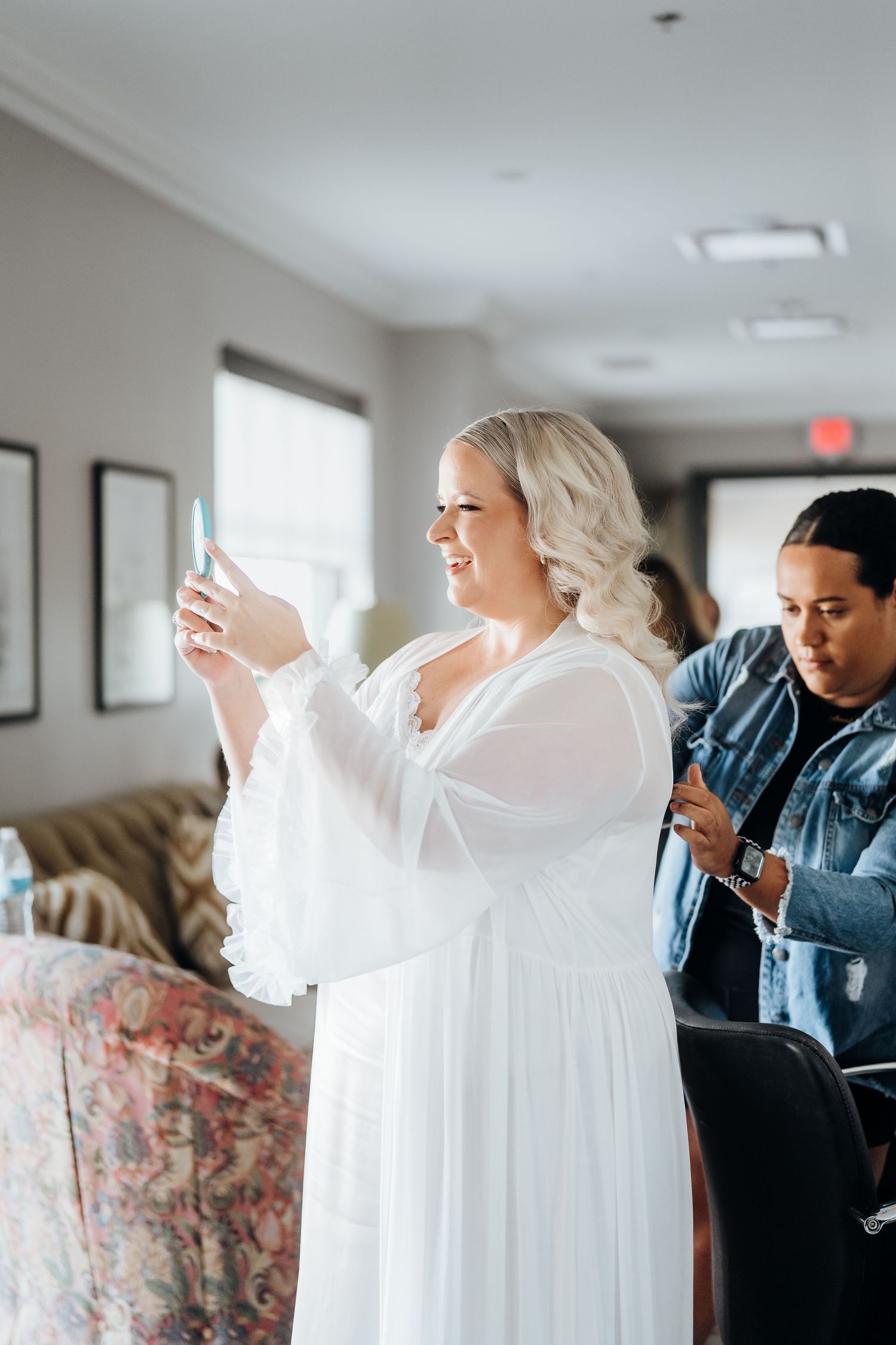 A white wedding dress being prepared and styled in a bright interior space.