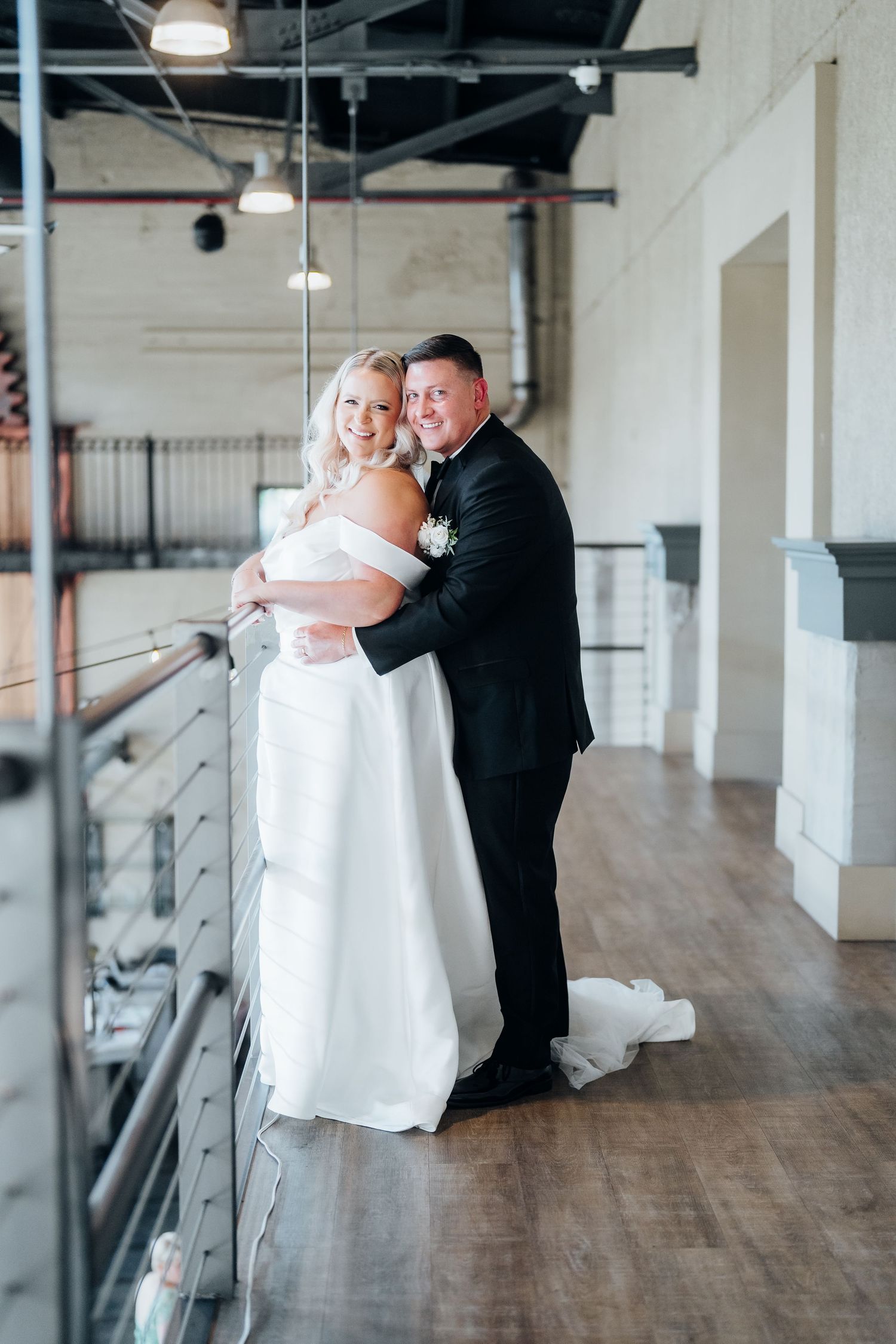 Couple dancing and twirling in an industrial-style wedding venue with wooden floors.