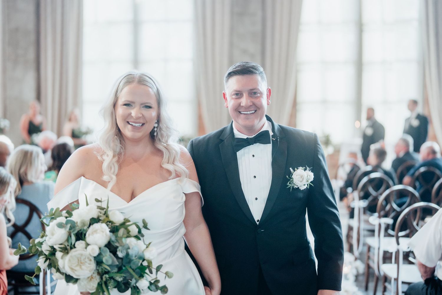 Elegant wedding reception setup with white floral arrangements and bright natural lighting.