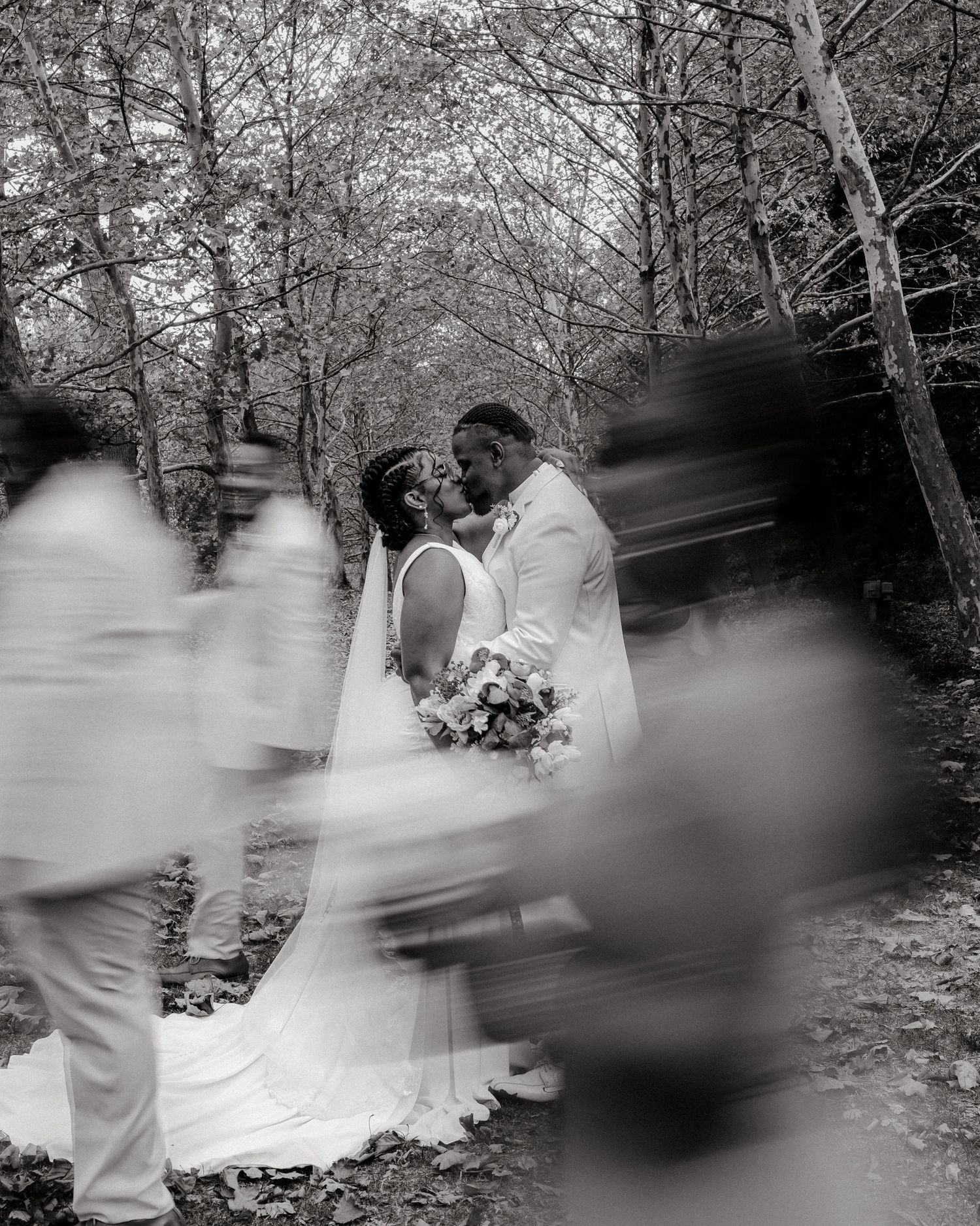 Artistic black and white motion blur of wedding party dancing in a wooded setting.