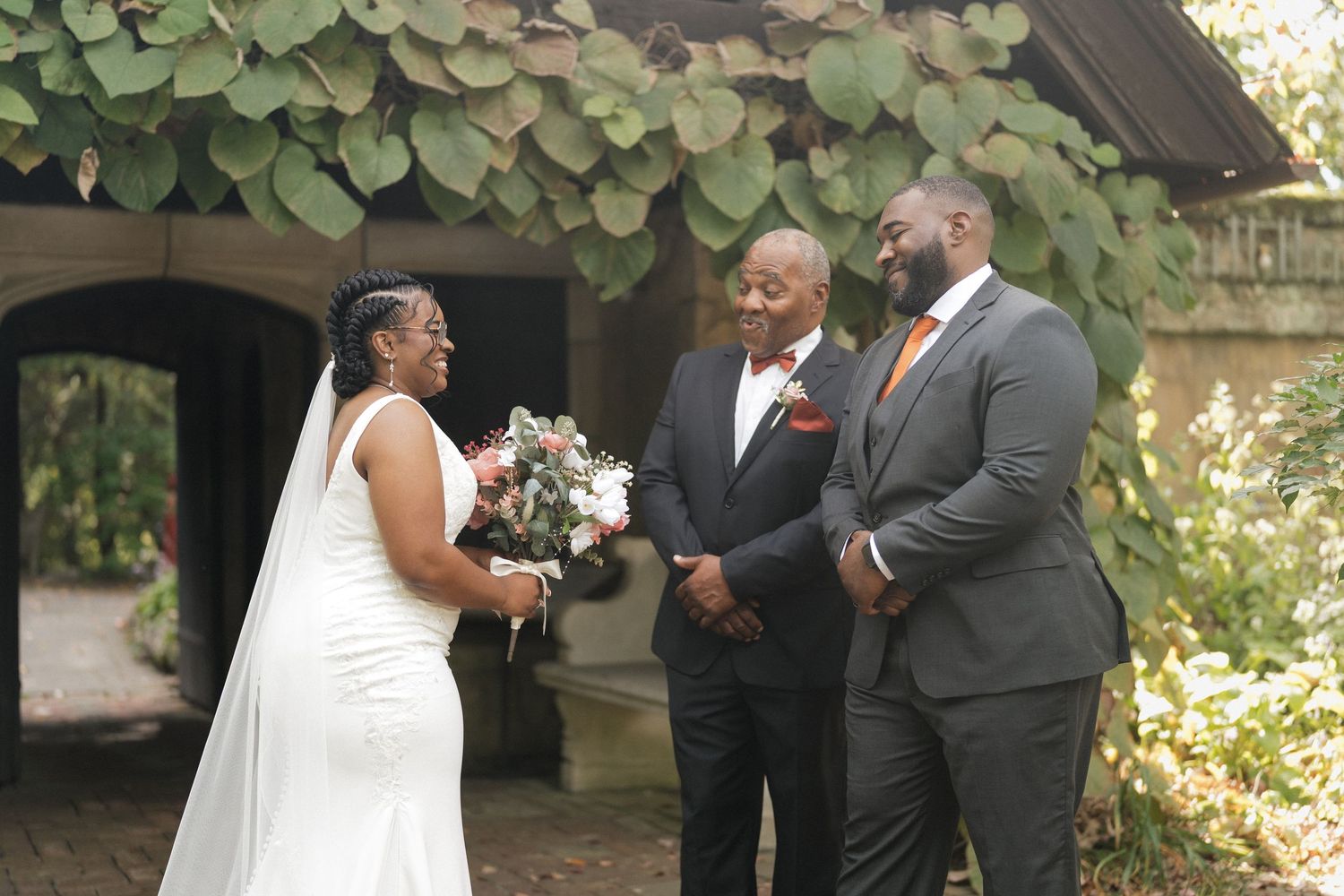 Wedding ceremony taking place in a lush garden setting with guests and officiant present.