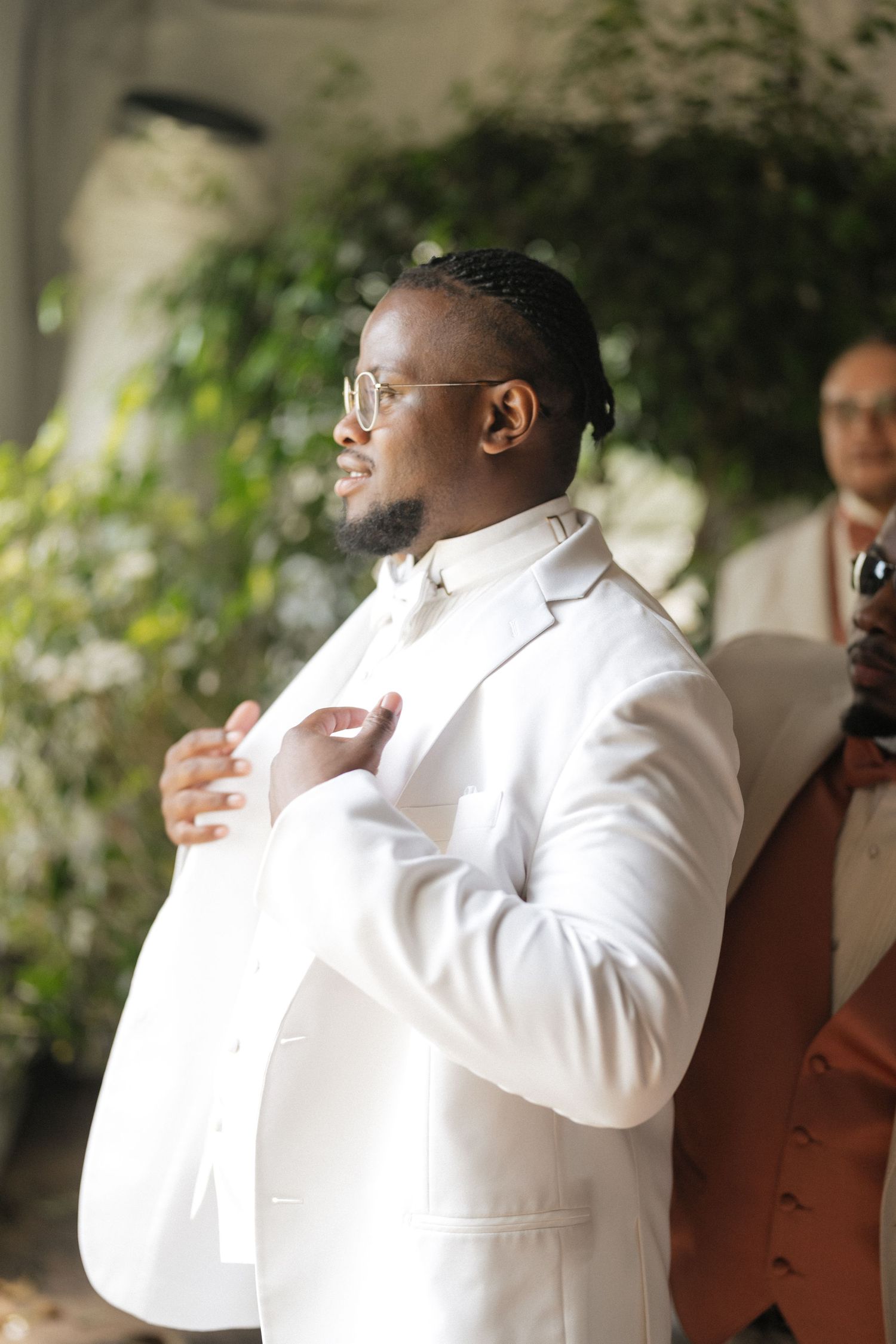 A series of candid shots showing a person in a white suit adjusting their tie and collar before a formal event.