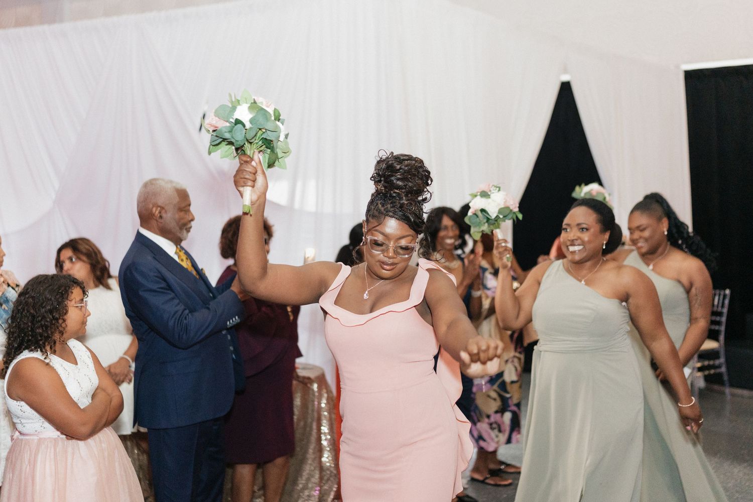 Wedding reception guests dancing and celebrating in an indoor venue.