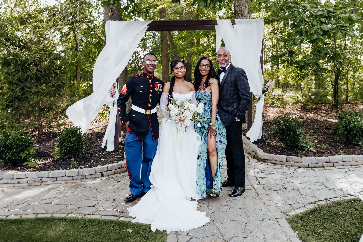Family formal portraits being captured at an outdoor wedding venue with stone pathways.