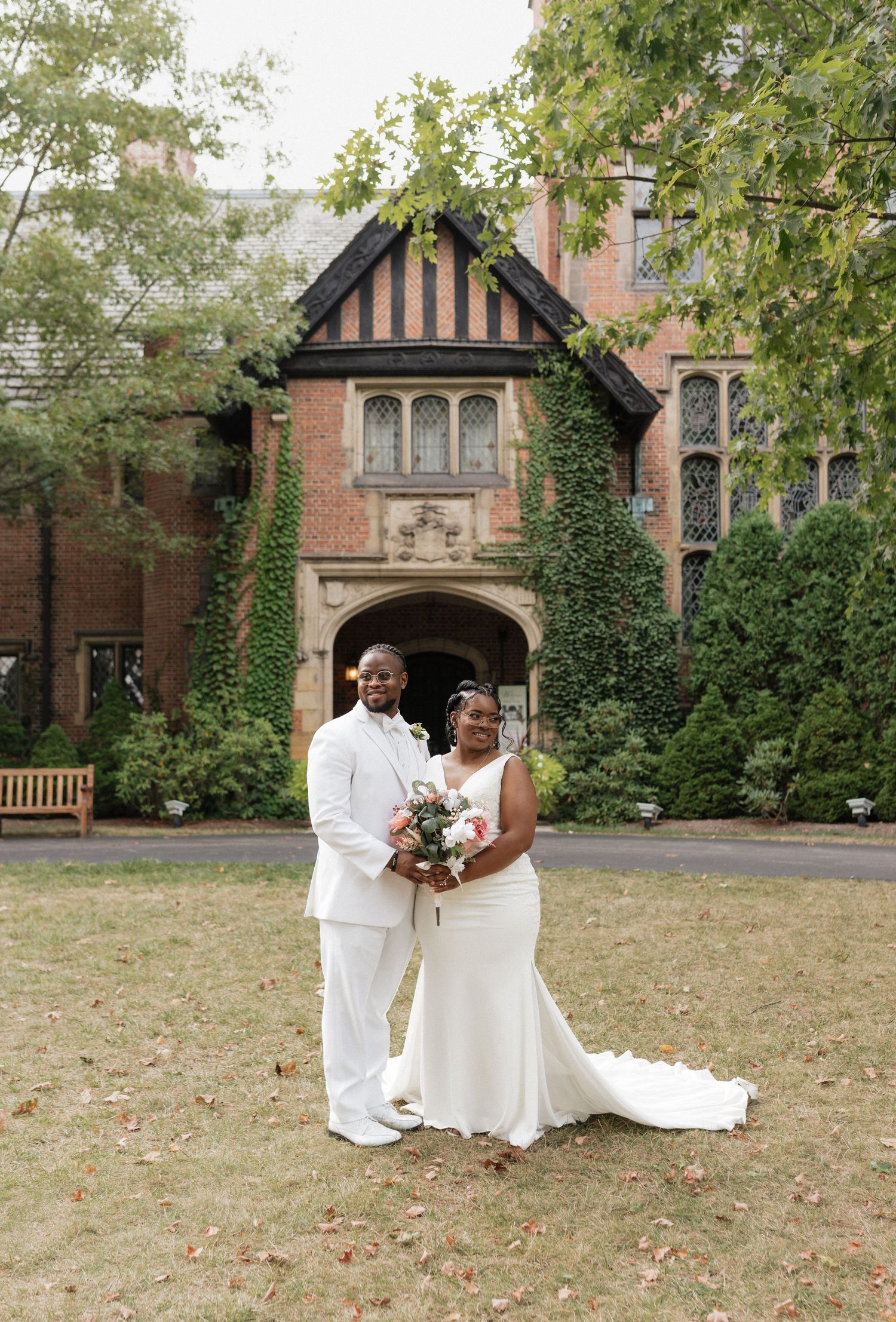 Wedding couple poses in front of historic brick building with Gothic architecture.