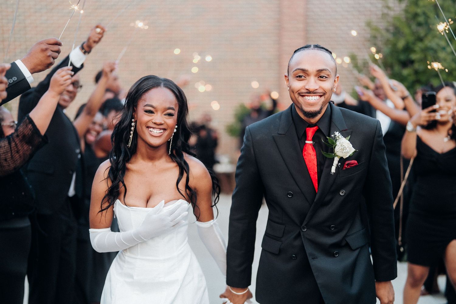 A joyful wedding exit with guests throwing confetti as the newlyweds walk together.